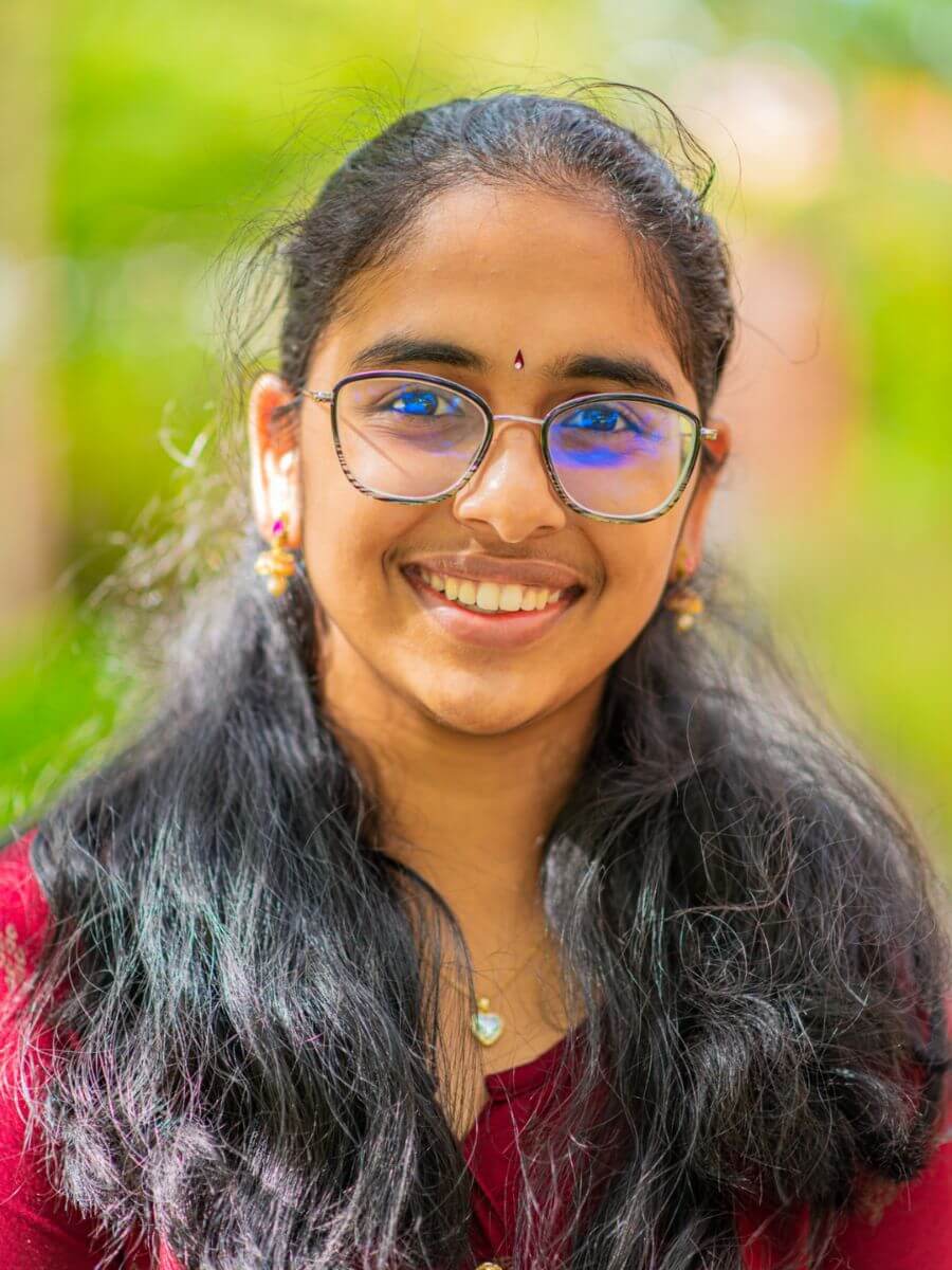 Amrutha Alibilli's headshot in front of a blurry green background 