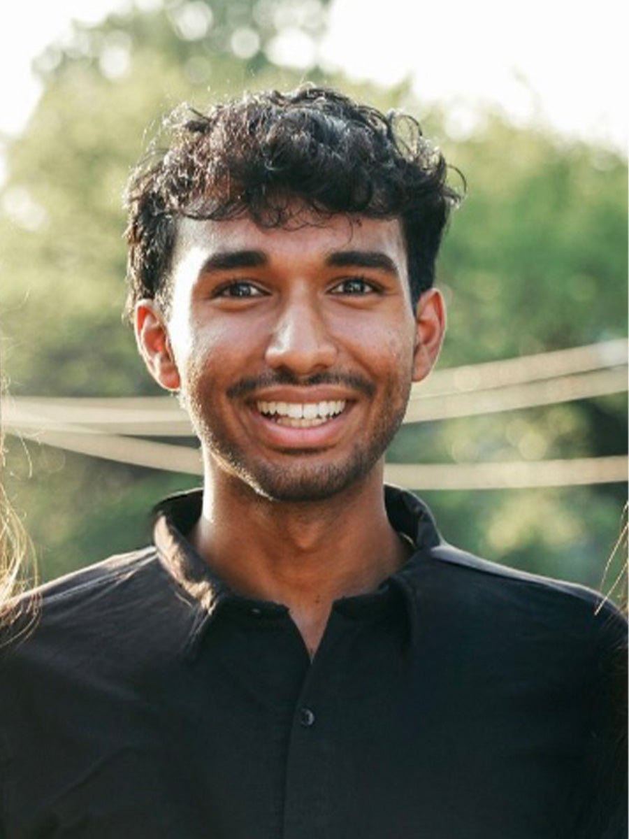 Aditya Sengar's headshot is him smiling with a blurry green background wearing a black collar shirt
