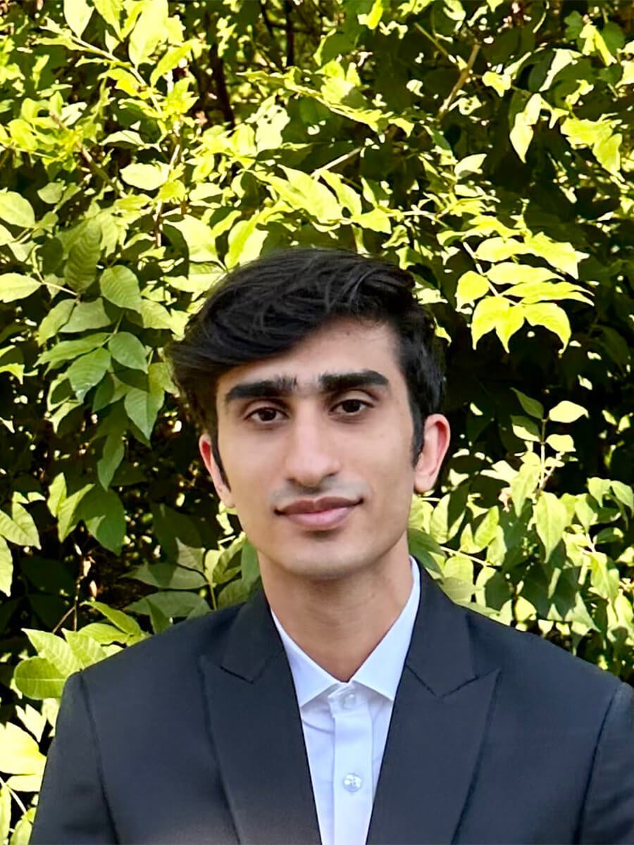 Kabir's headshot features a young man with black hair wearing a white shirt and black blazer.