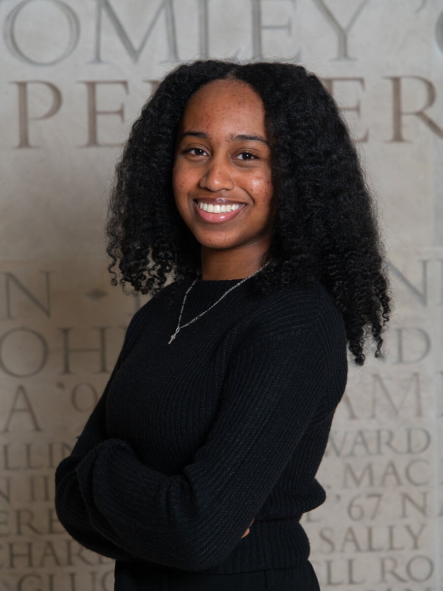 Headshot of a woman smiling and crossing her arms while wearing a black long sleeve top 
