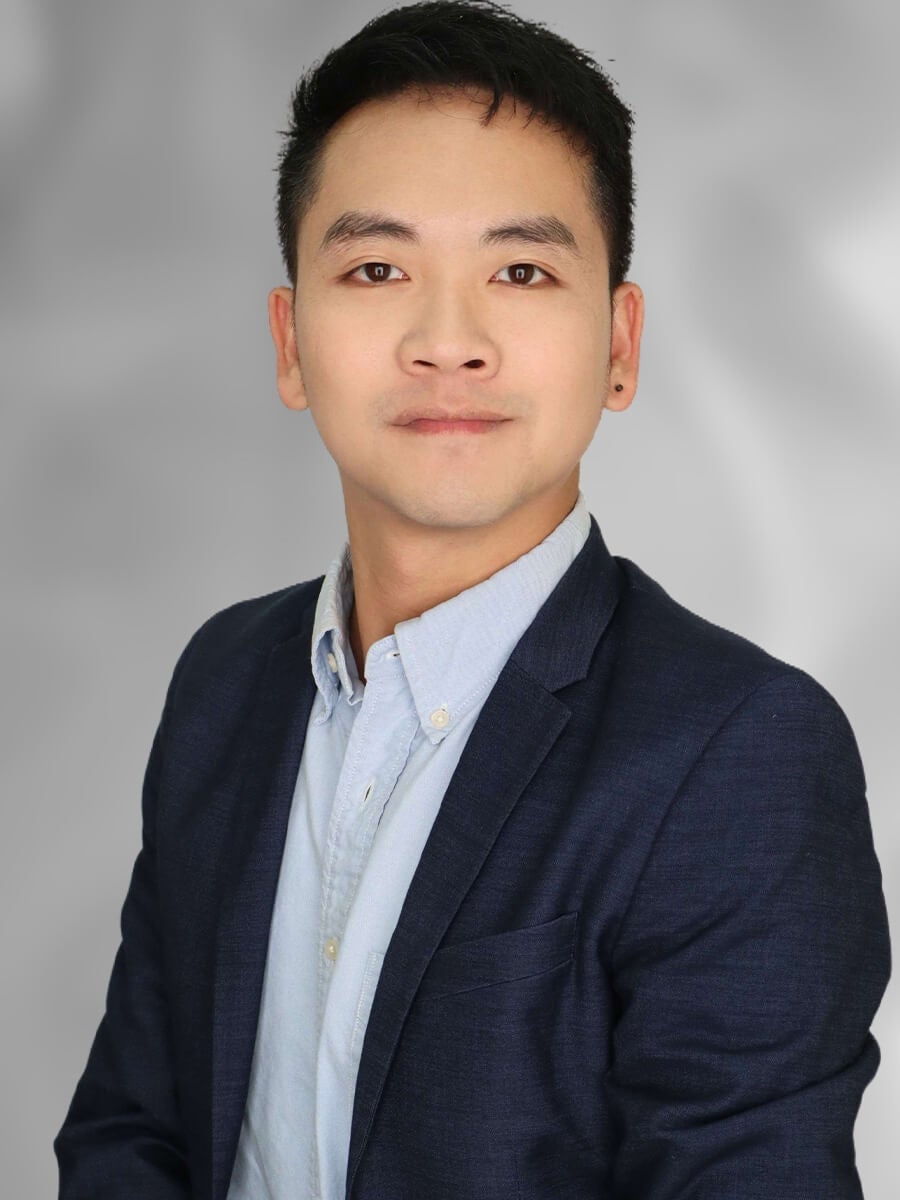 Man posing for a headshot wearing a black blazer and grey collar shrit