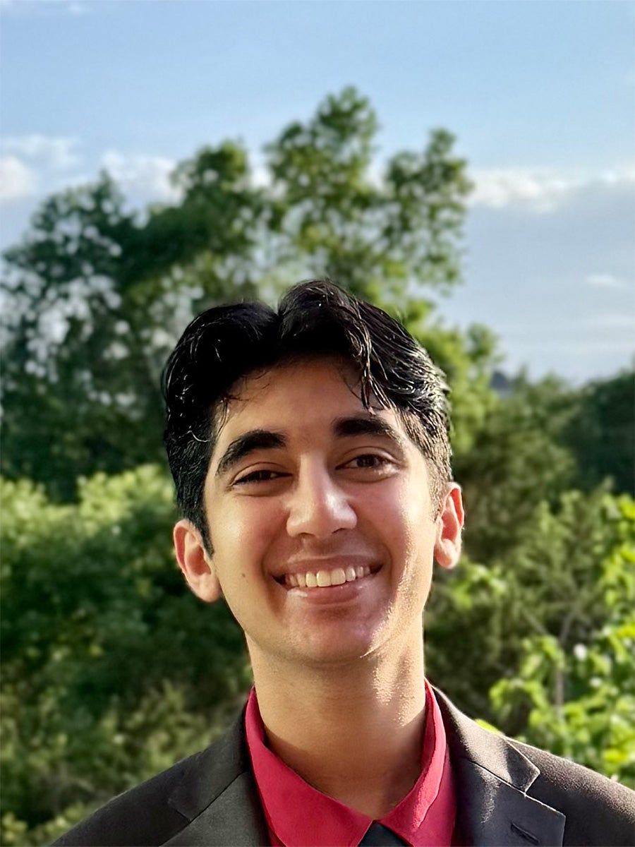 Headshot of student in a black suit with a red shirt
