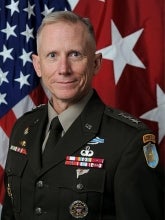 headshot of DA Sims, a man with a flag in the background and a decorated military jacket