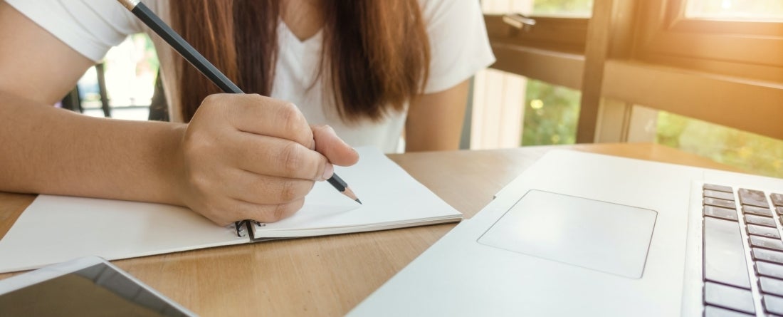 student on a laptop taking notes