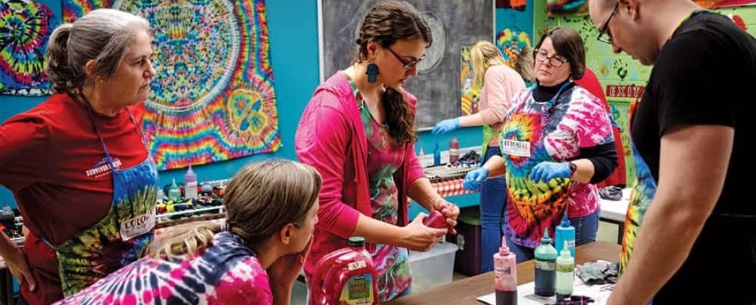 A group of people are all tye-dying shirts 