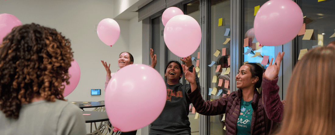 ChangeMakers celebrating the conclusion of their program by playing with pink balloons, tossing them into the air.