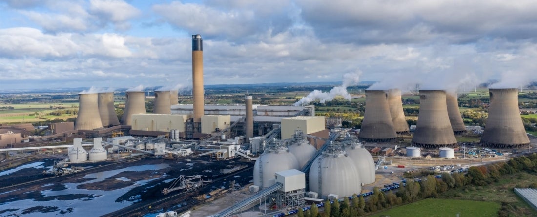 Aerial view of biomass fuel storage tanks with carbon capture capabilities with blue skies and clouds.