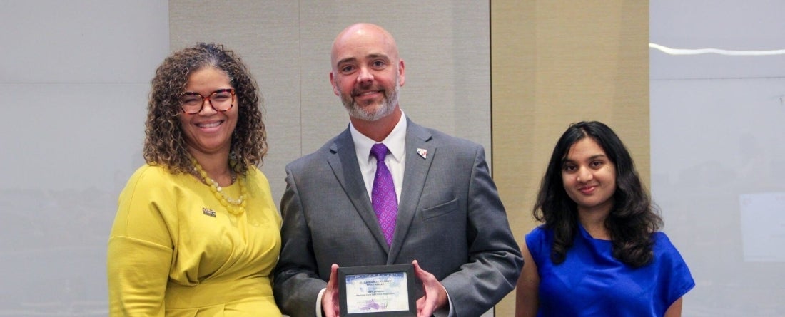 Brandi Slaughter wearing a yellow dress, Sean Johnson in gray suit and current Pizzigati fellow in blue shirt pose for a picture