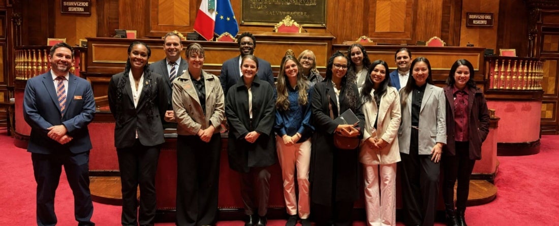students visit the Italian Senate Chamber with red carpet and wooden backdrop