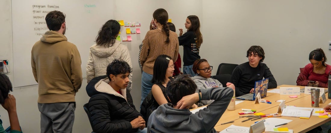 Group of students working together on a white board in a classroom-like setting.