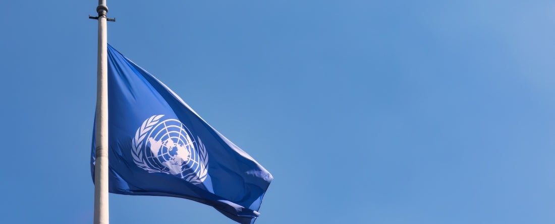 The United Nations flag with a clear blue sky background