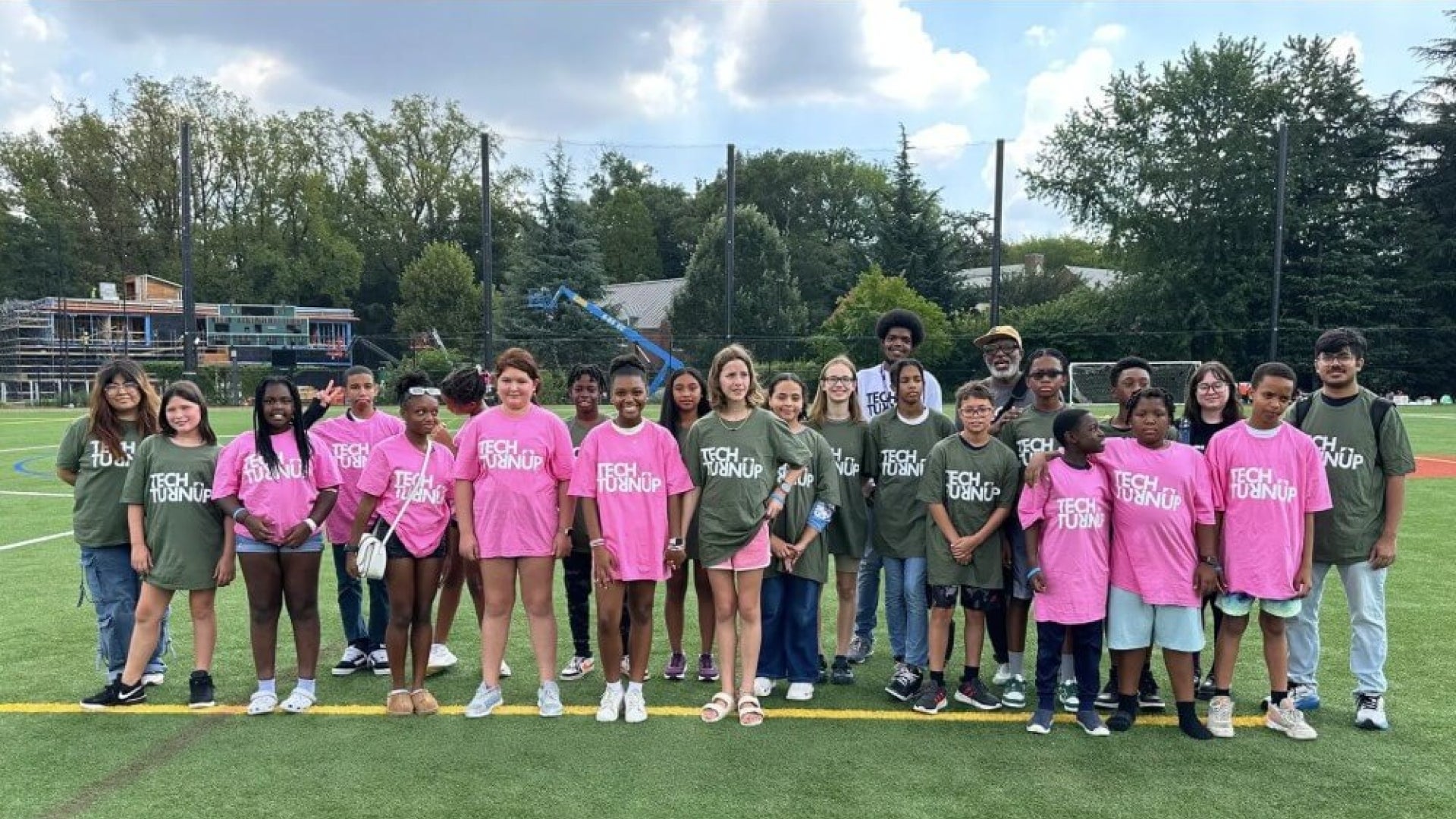 Group of people on athletic field wearing pink or green t-shirts that say "Tech TurnUp"