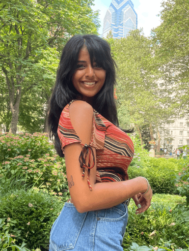 Eveleen is standing in a park and smiling